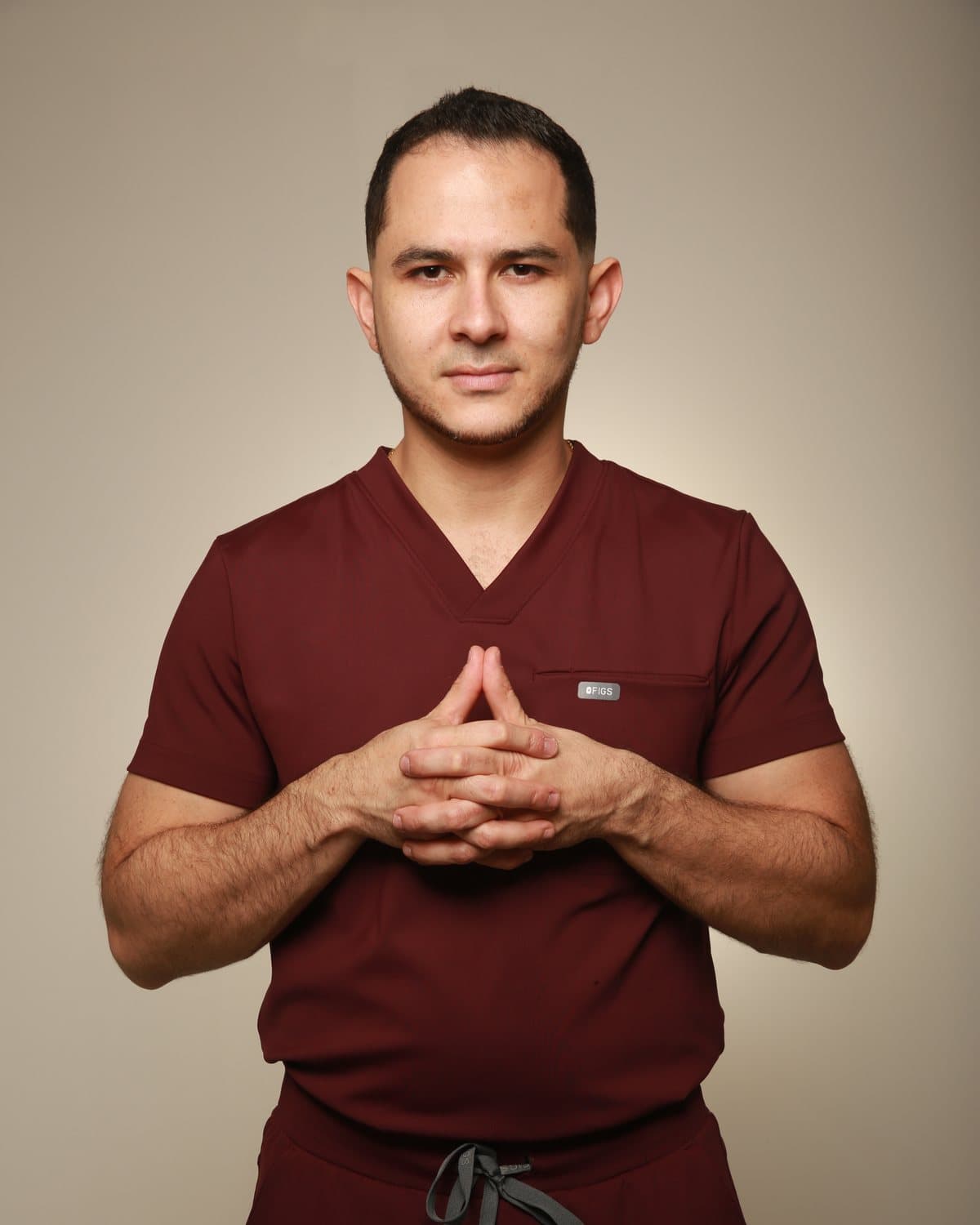 Dr. Pedro León Amaya con uniforme quirúrgico burdeos